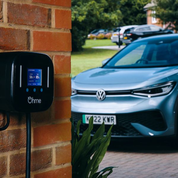 Ohme charger mounted on brick wall, VW ID4 in background